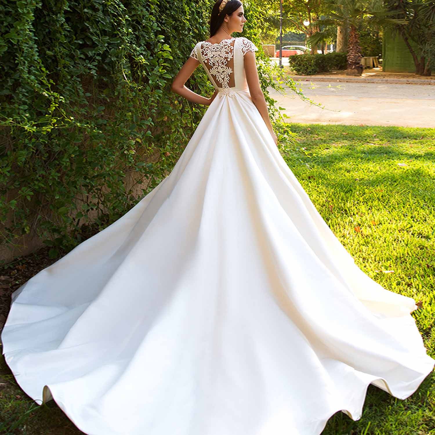 Stunning back view of a satin wedding dress showcasing an exquisite sheer illusion mesh back with royal lace embroidery and trailing button closures.