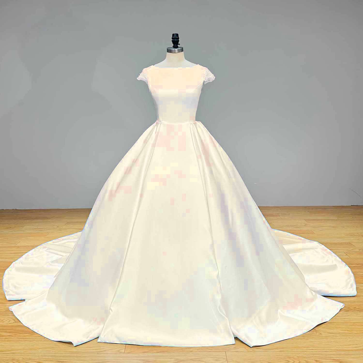 Classic off-white satin ball gown wedding dress featuring a modern boat neckline and seamless a-line silhouette on a studio mannequin.