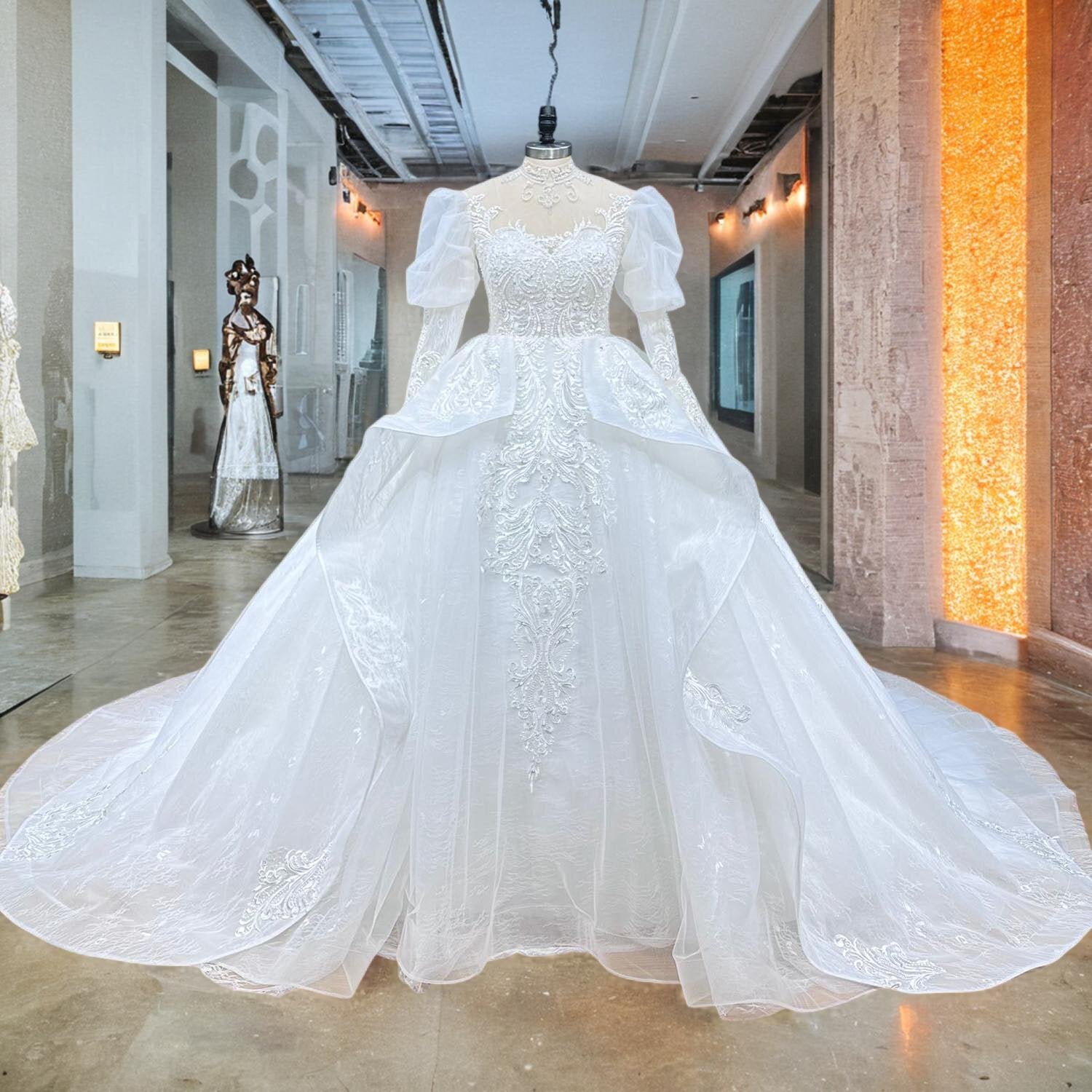 Front studio display of a high-neck puff sleeve beaded ball gown on a mannequin, highlighting the structured bodice, vintage-inspired sleeves, and voluminous tulle skirt.