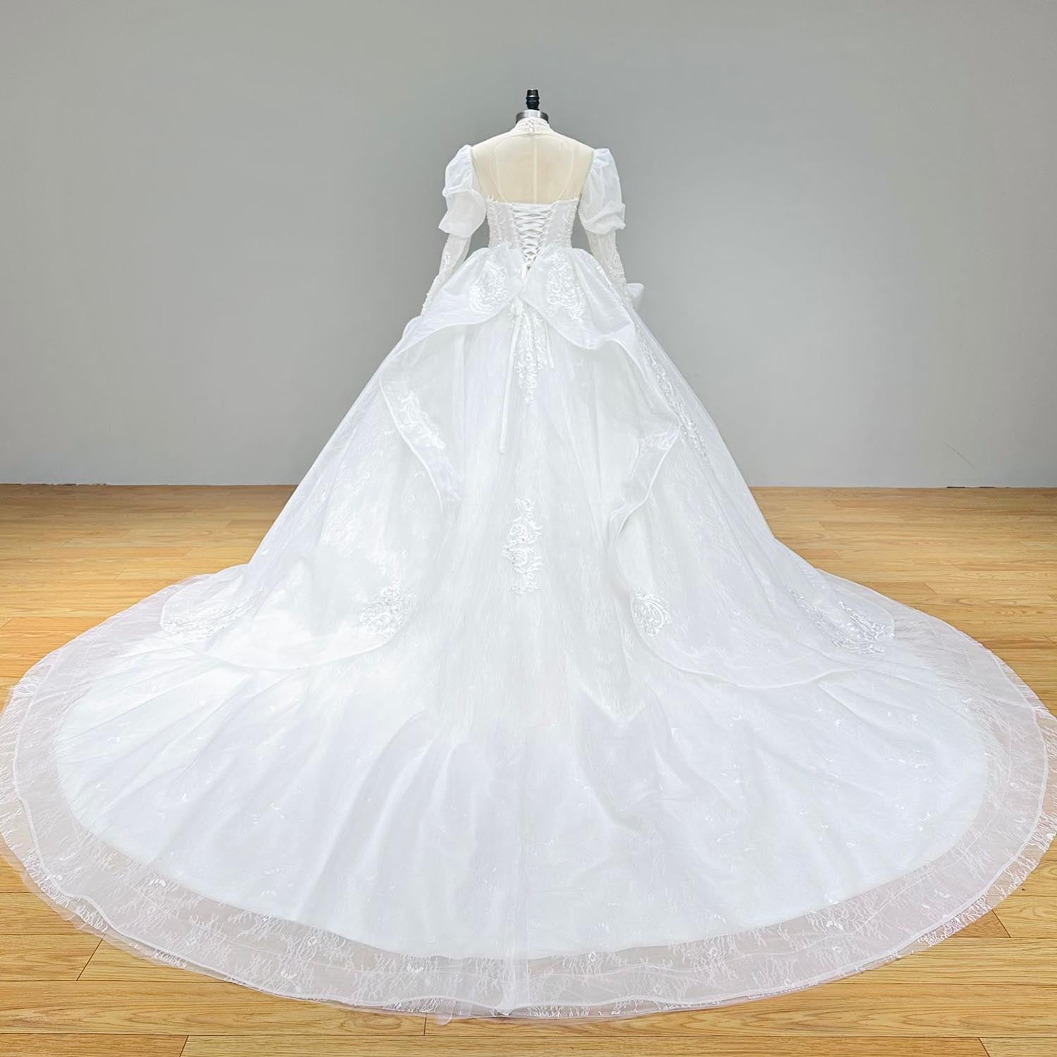 Back view of an elegant high-neck puff sleeve bridal ball gown on a mannequin, featuring a delicate button-back closure and a sweeping lace-trimmed cathedral train.