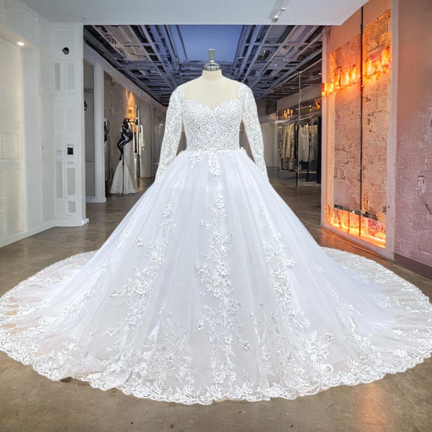 Bridal mannequin wearing a long-sleeve beaded ball gown wedding dress featuring a voluminous lace-embellished skirt.