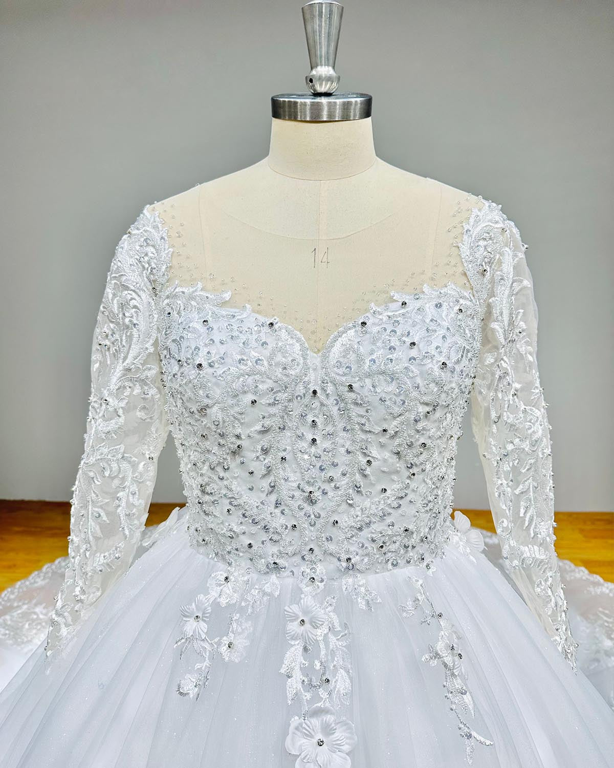 Close-up detail of the sweetheart neckline and intricate beaded bodice on a long-sleeve bridal ball gown.