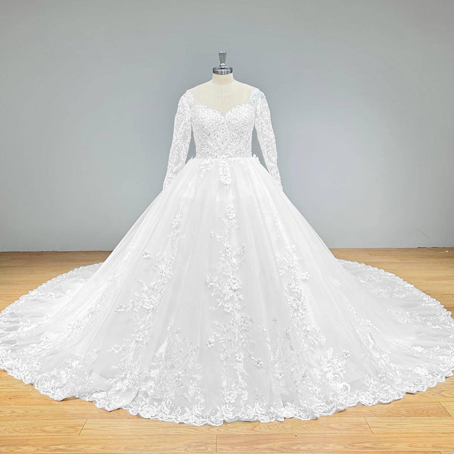 Full-length front view of a luxury long-sleeve beaded ball gown wedding dress with floral embroidery and a wide train on a mannequin.
