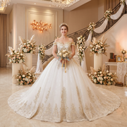 Bride posing in a luxury white and gold off-shoulder ball gown wedding dress with beaded lace at a grand indoor ceremony venue.