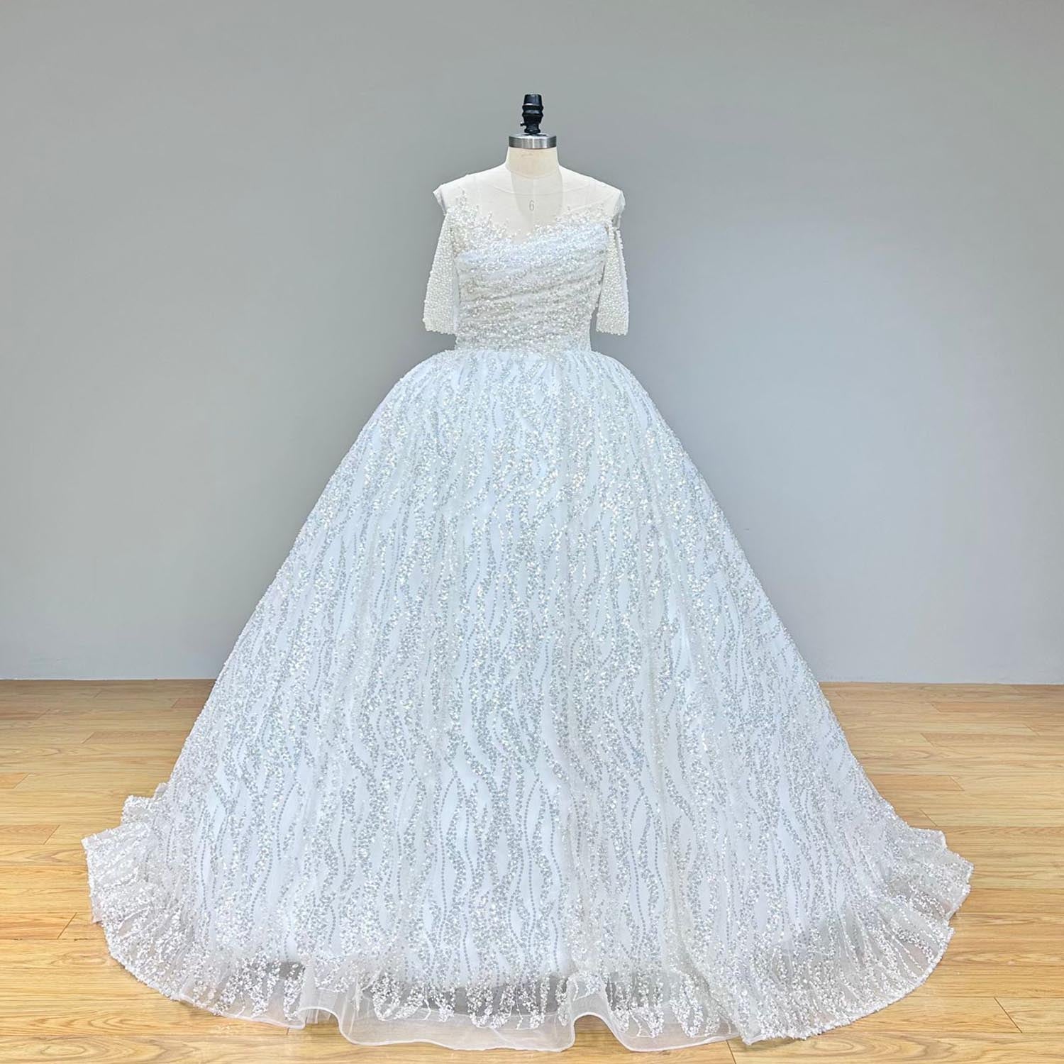 A sparkling ball gown wedding dress with short sleeves and a detailed beaded bodice displayed on a mannequin.