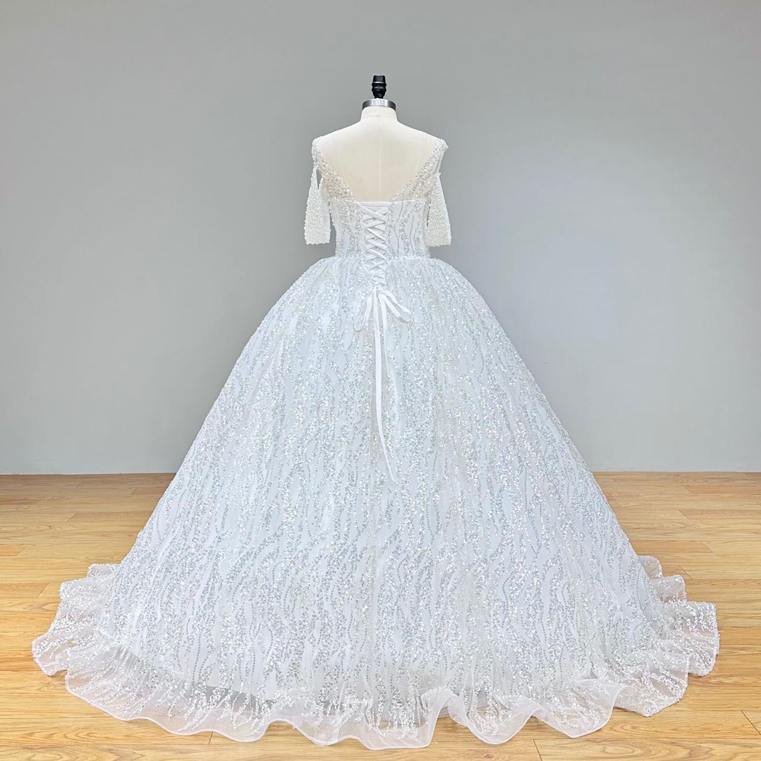 Back view of a luxurious ball gown wedding dress featuring a lace-up corset closure and intricate pearl beading.