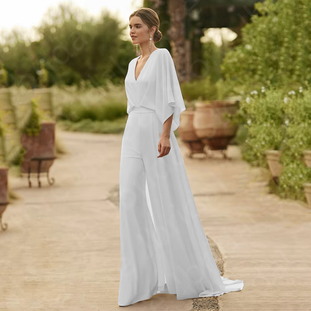 High-resolution full portrait of the modern white wedding jumpsuit with a plunged V-neckline and dramatic wide-leg pants, perfect for a destination or outdoor bridal look.