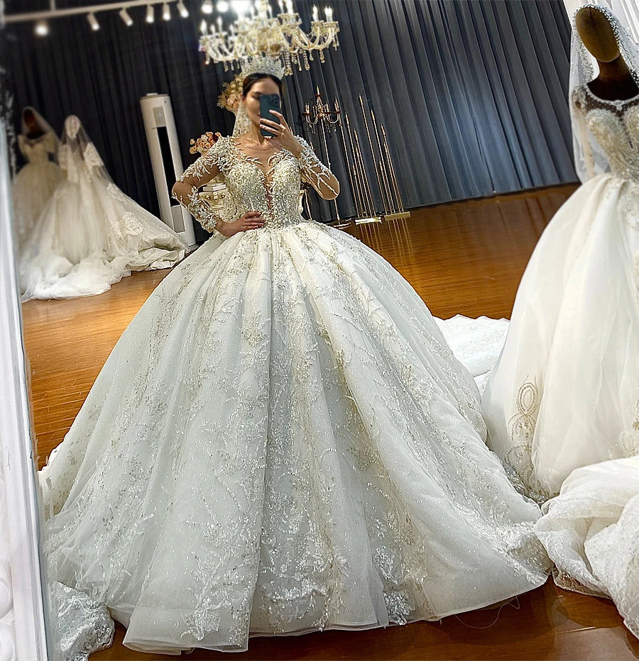Mirror selfie highlighting the royal puffy luxury design and shimmering silver embroidery of a long-sleeve princess ball gown wedding dress.
