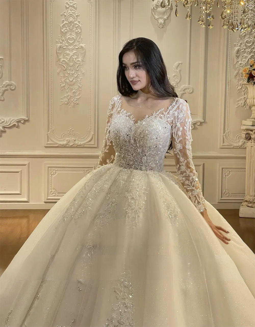 Close-up of the bodice on a luxury long sleeve wedding dress, showcasing the plunging illusion V-neckline and dense, hand-crafted silver crystal beadwork.