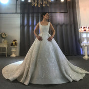 Full-length front view of an elegant sleeveless ball gown wedding dress with a heavily beaded square neck bodice and a voluminous sparkling skirt featuring branch-motif embroidery.