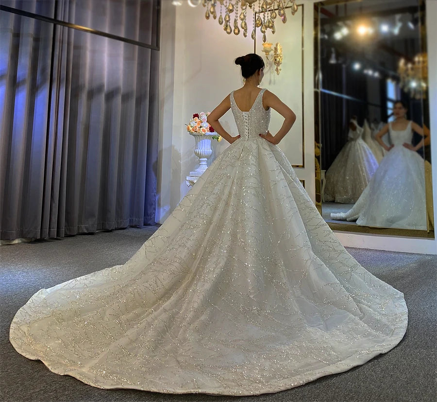 Breathtaking rear perspective of a luxury ball gown wedding dress, emphasizing the expansive cathedral-length train covered in radiant branch-patterned sequins.