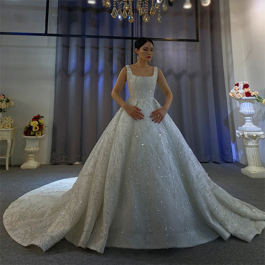 Stunning front profile of a sleeveless ball gown wedding dress with a regal silhouette, all-over crystal beading, and a wide-sweeping sparkling skirt for a luxury bridal look.