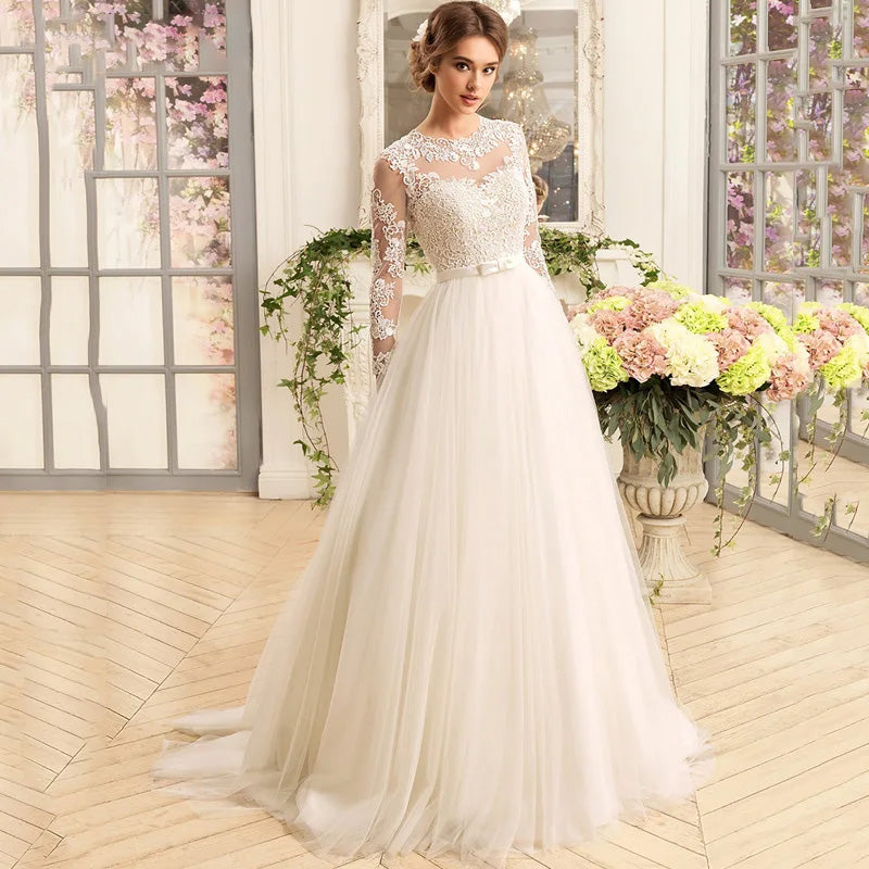 An elegant bride wearing a luxury A-line wedding dress with an illusion lace back and classic O-neck, posing in a sophisticated indoor setting.