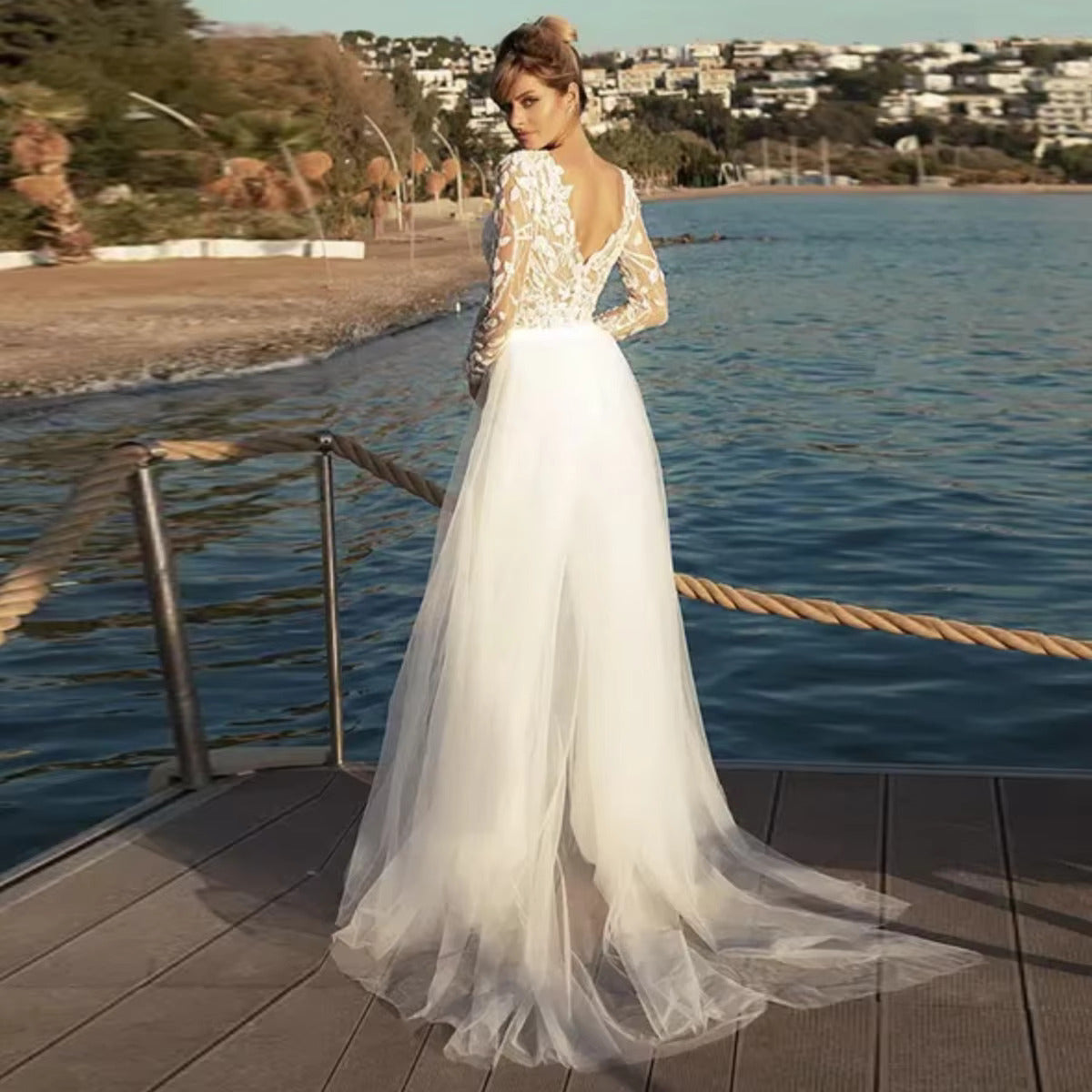Alternate back view of the modern bridal pantsuit ensemble, showcasing the lightweight sweep of the removable sheer tulle outlayer train against a scenic coastal backdrop.
