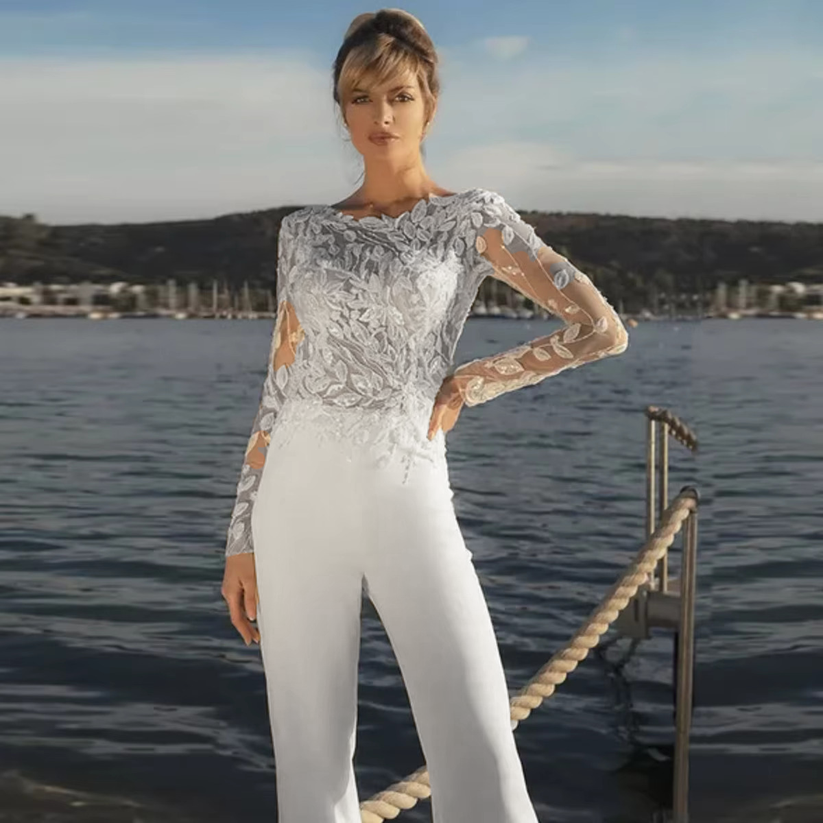 High-resolution front shot of the long-sleeve illusion lace top wedding jumpsuit without the overskirt, showing the clean, minimalist stretch pants look in a soft white tone.