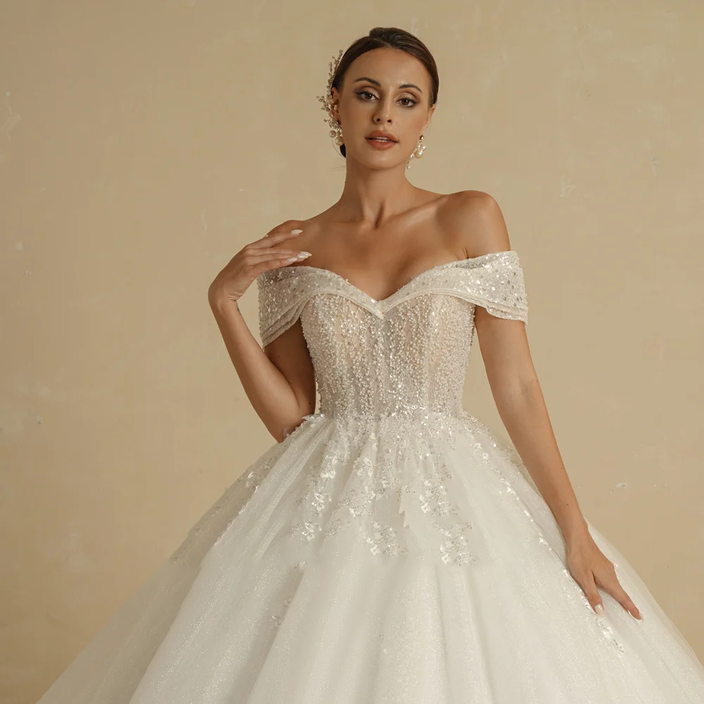 Rear view of a vintage-inspired ivory ball gown wedding dress with a lace-up corset back and a flowing court train.