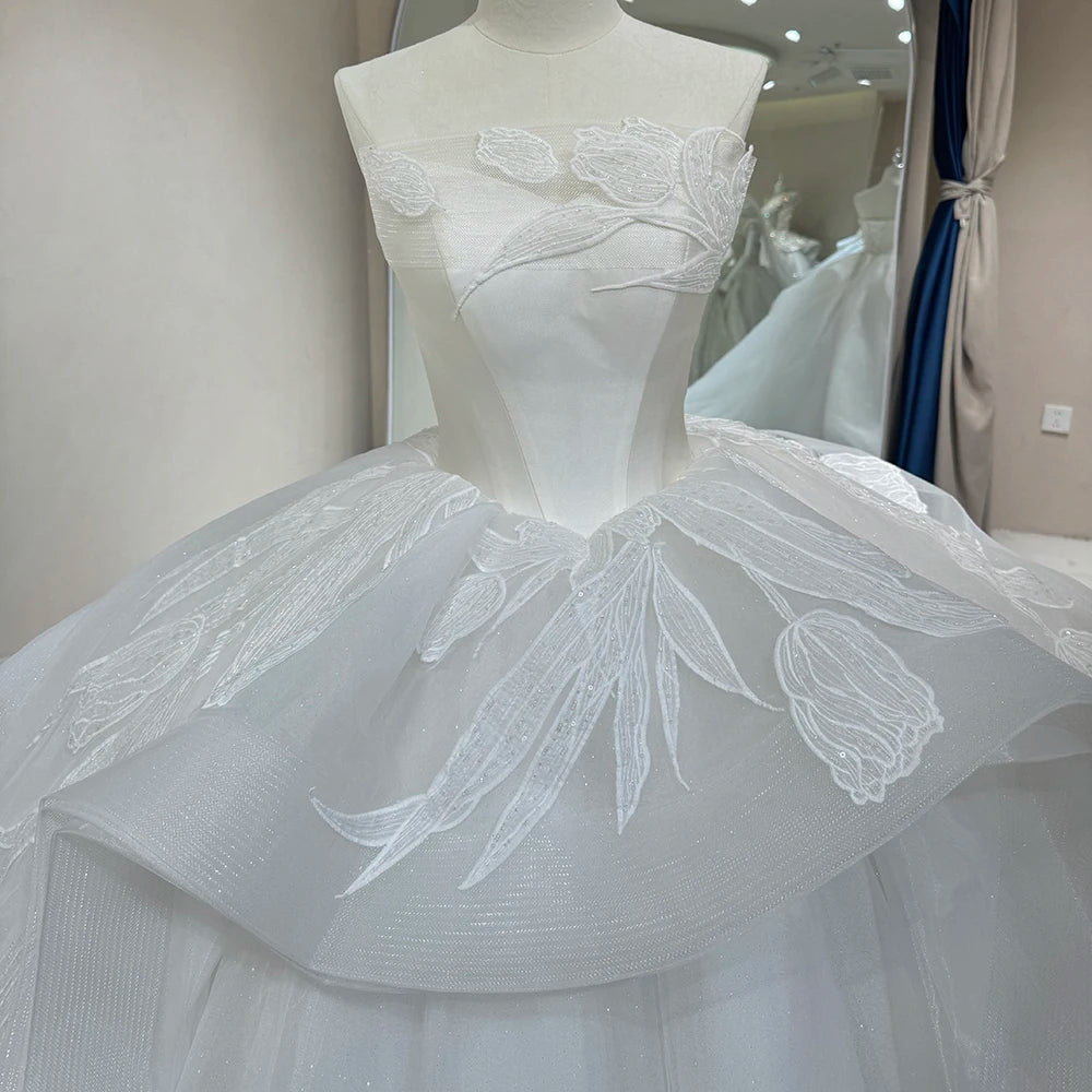 Comprehensive back profile of a strapless ivory glitter bridal gown, showcasing the wide-sweep shimmering train and royal ball gown scale on a mannequin.