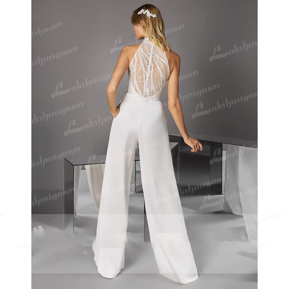 Full-length back view of the ivory bridal pantsuit, showcasing a sheer high-neck back with detailed linear sequins and button closures, along with high-waisted trousers with side pockets.