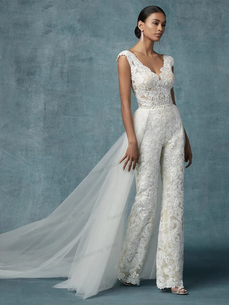 A bride wearing a sophisticated lace bridal jumpsuit featuring an elegant detachable tulle train.
