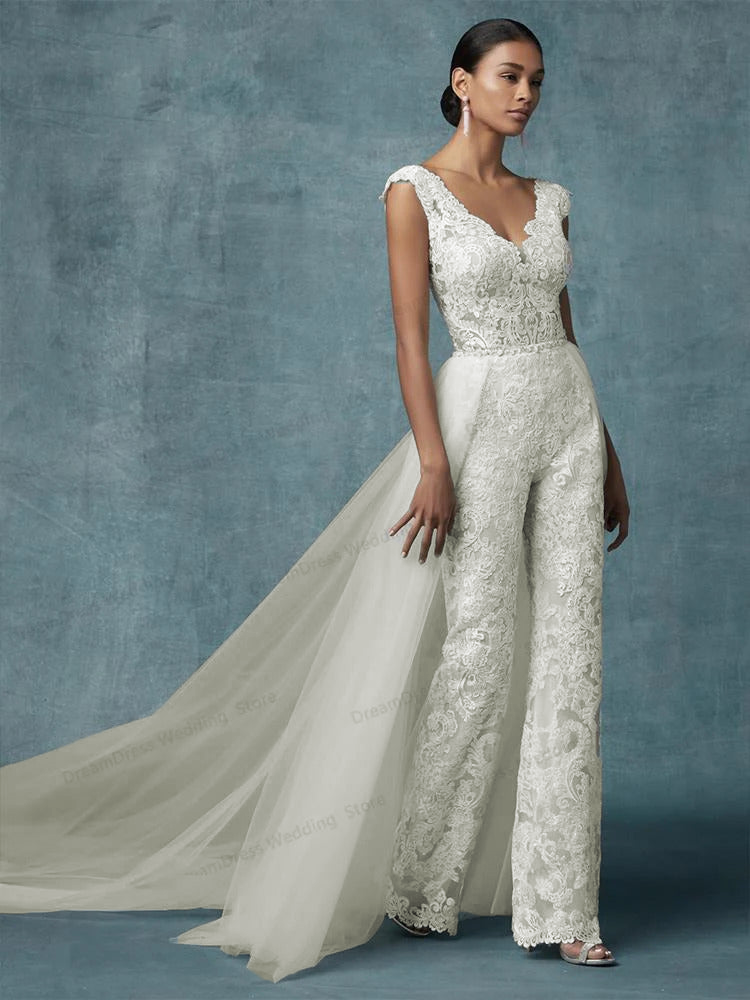 A full-length portrait of a bride in a lace bridal jumpsuit with a detachable train, combining style and modern elegance.