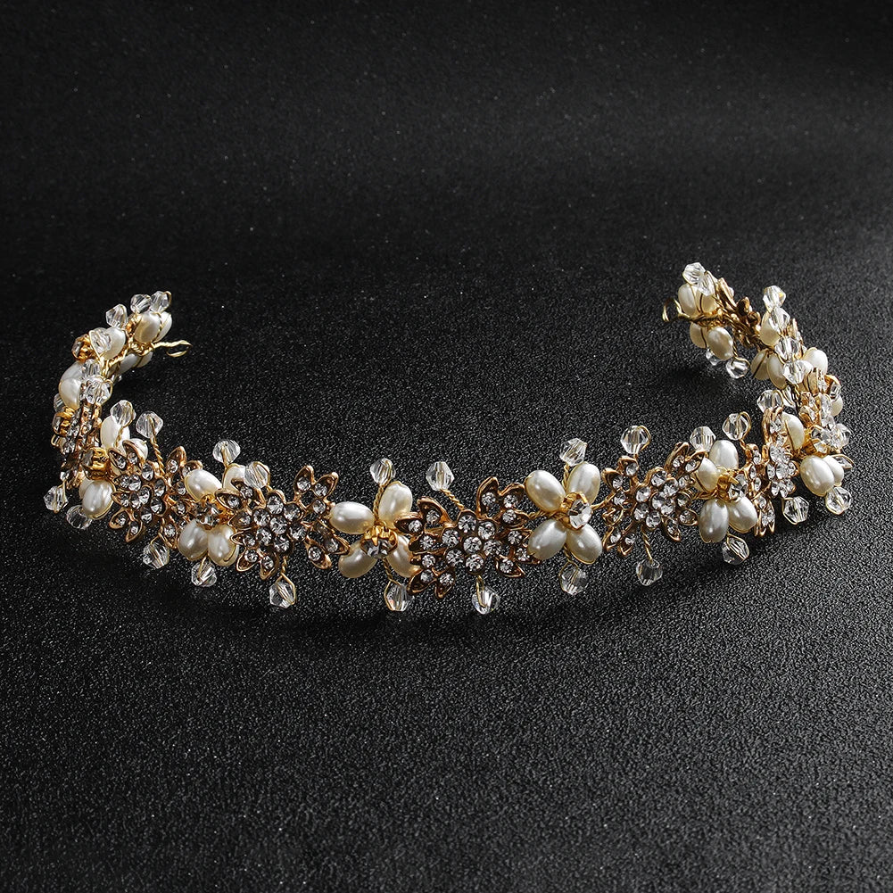 Close-up view of a gold-toned handmade bridal hairband featuring pearl flowers and crystal accents on a dark background.