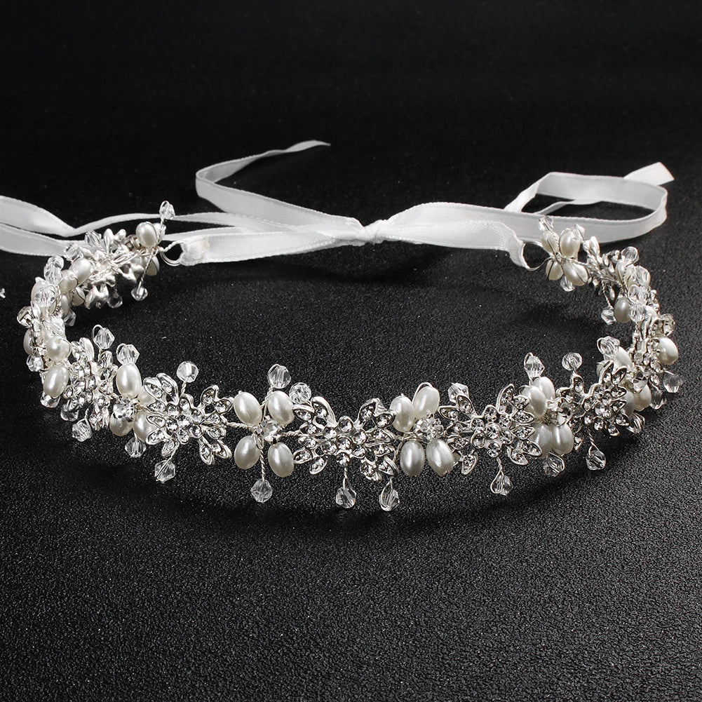 Close-up of a silver-toned pearl flower bridal hairband featuring white ribbons for an adjustable wedding hairstyle.