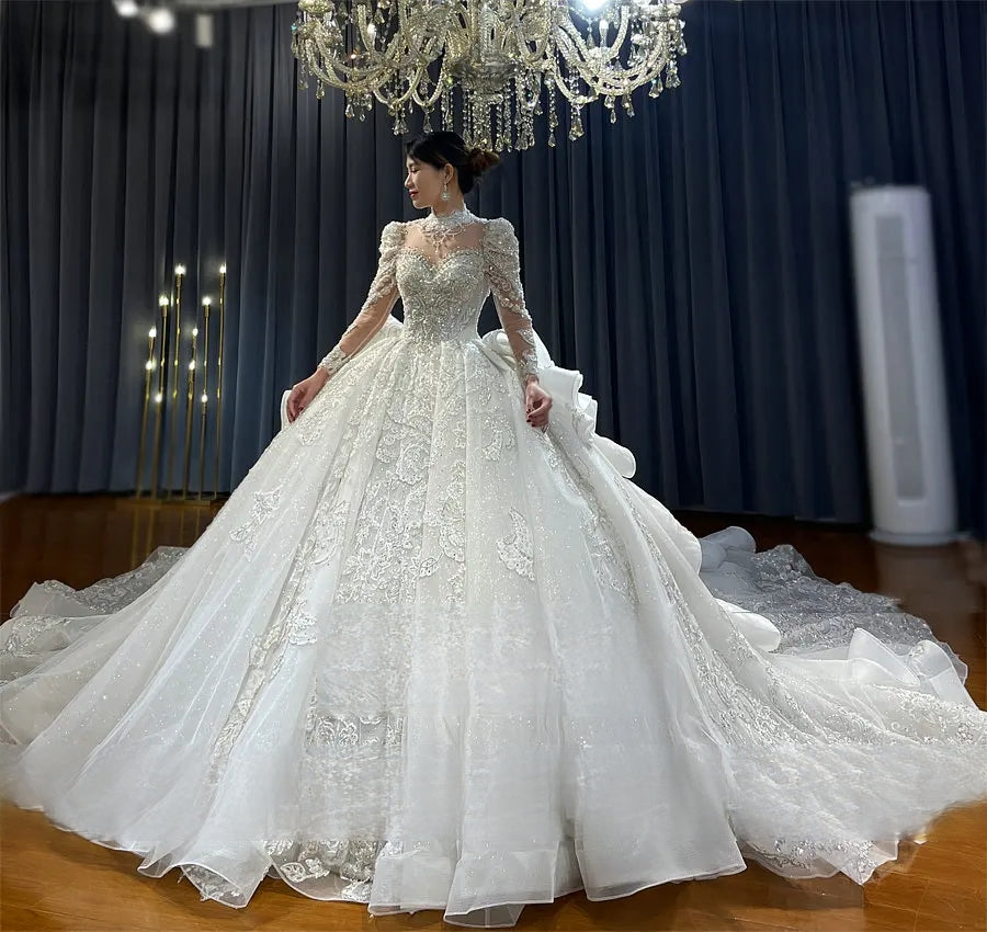 Elegant high-neck bridal ball gown with intricate lace detailing, shimmering crystal embellishments, and a voluminous skirt in a luxury studio setting.