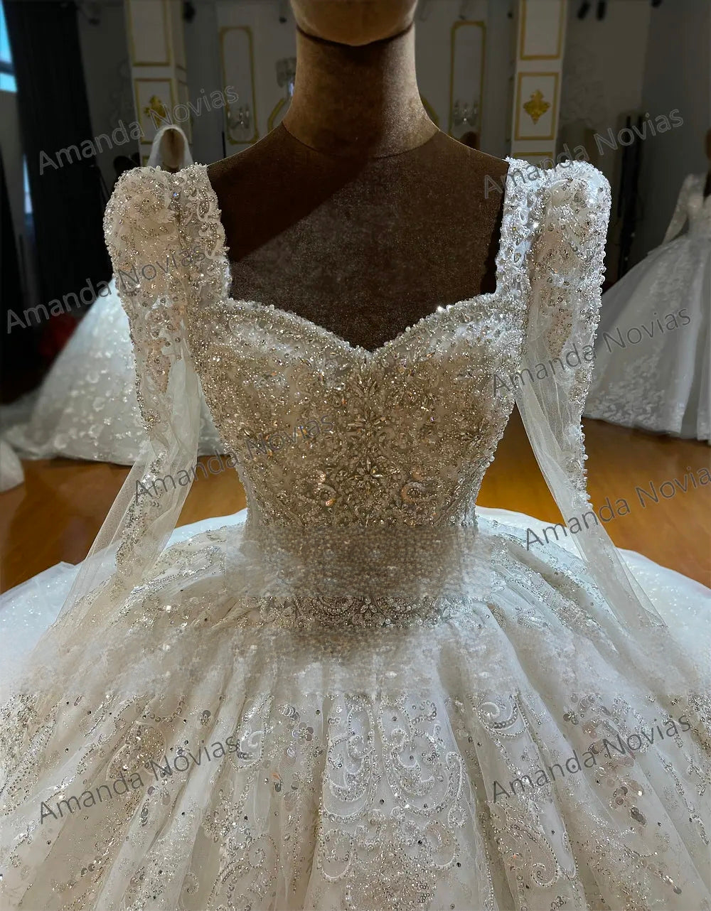 Close-up detail of a luxury bridal bodice with full sleeves, emphasizing the exquisite square neckline, dense silver crystal embroidery, and sparkling lace appliqués.