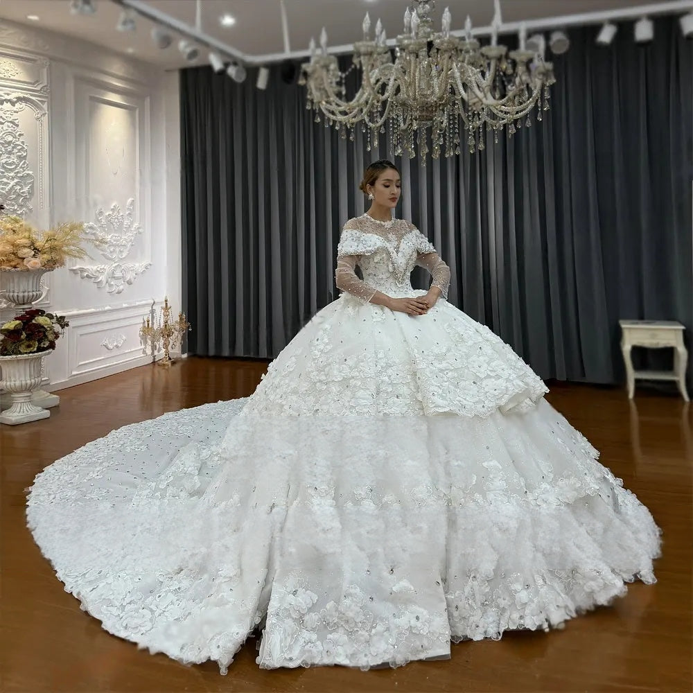 Front perspective of a bride in a luxury ball gown wedding dress showcasing the voluminous tiered layered skirt and detailed silver crystal and lace flower embroidery on the bodice.