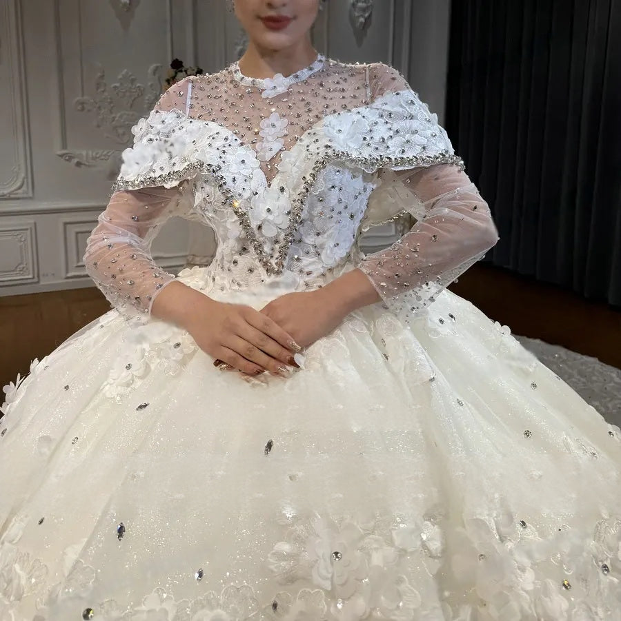 Close-up detail of the luxury bridal bodice, highlighting the plunging V-neckline, sheer long sleeves, and handcrafted 3D lace flowers with silver sequin and crystal accents.