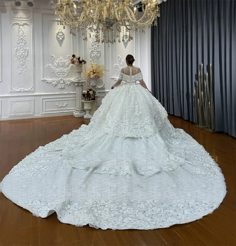 Detailed back view of a luxury bridal ball gown on a mannequin, emphasizing the wide, shimmering tiered organza layers of the train and the elegant sheer illusion back.