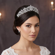 Headshot portrait of a brunette bride with a classic low bun hairstyle wearing a high-quality cubic zirconia leaf bridal wedding tiara crown and small matching drop earrings.