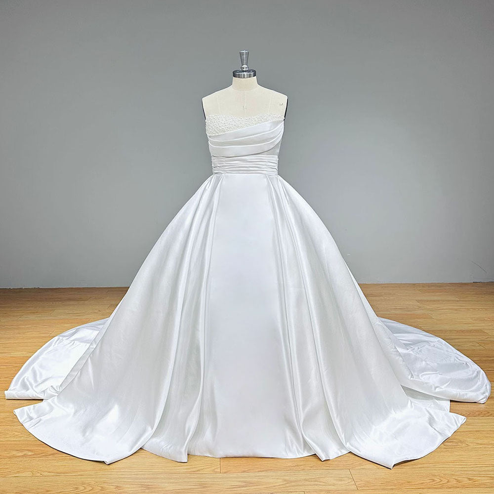 Full-length front perspective of the contemporary heavy satin bridal gown on a dress form against a solid gray studio background, highlighting its premium tailoring.