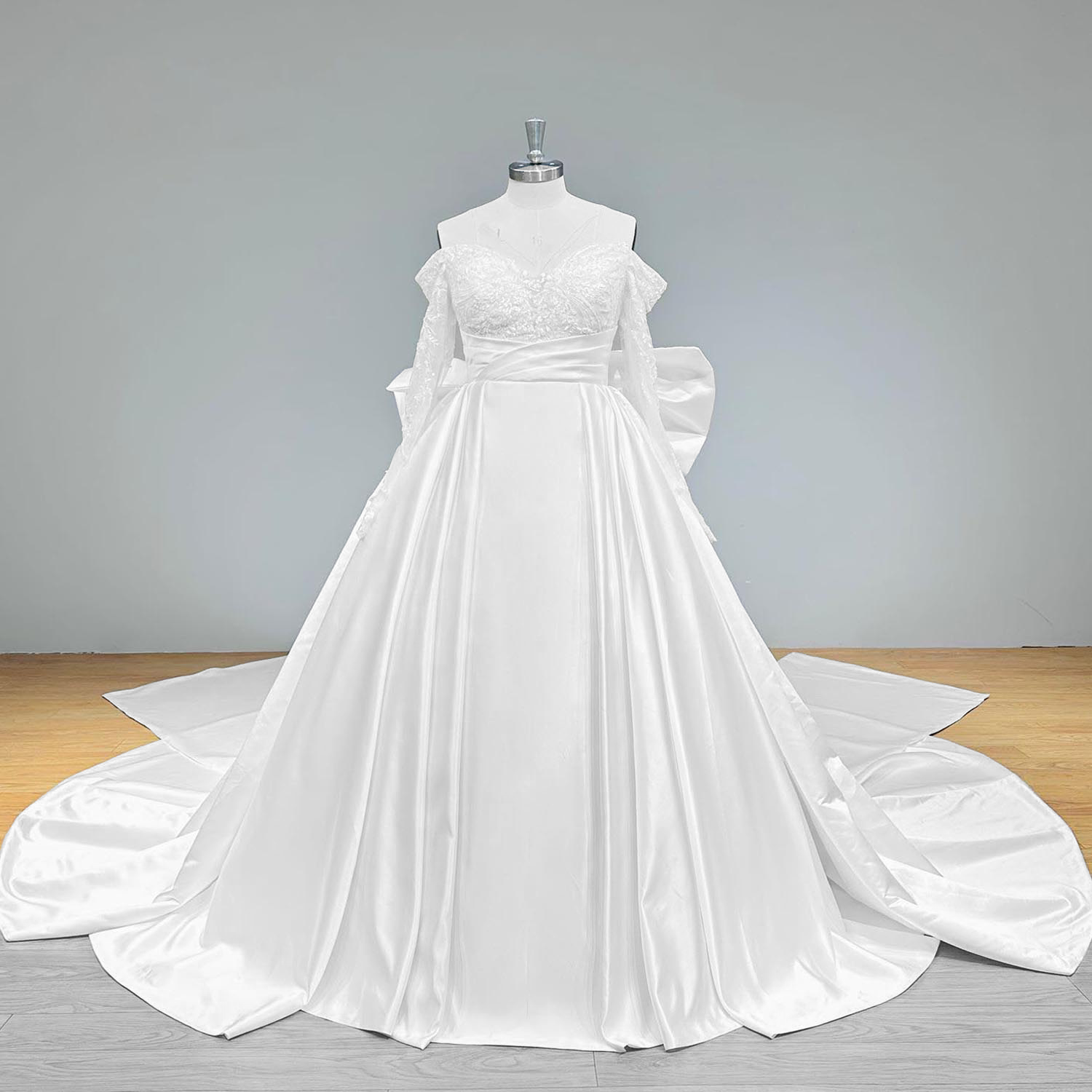 Wide front view of a classic light effect satin wedding dress on a mannequin, perfectly displaying the smooth A-line silhouette, lace long sleeves, and wide flowing chapel train.