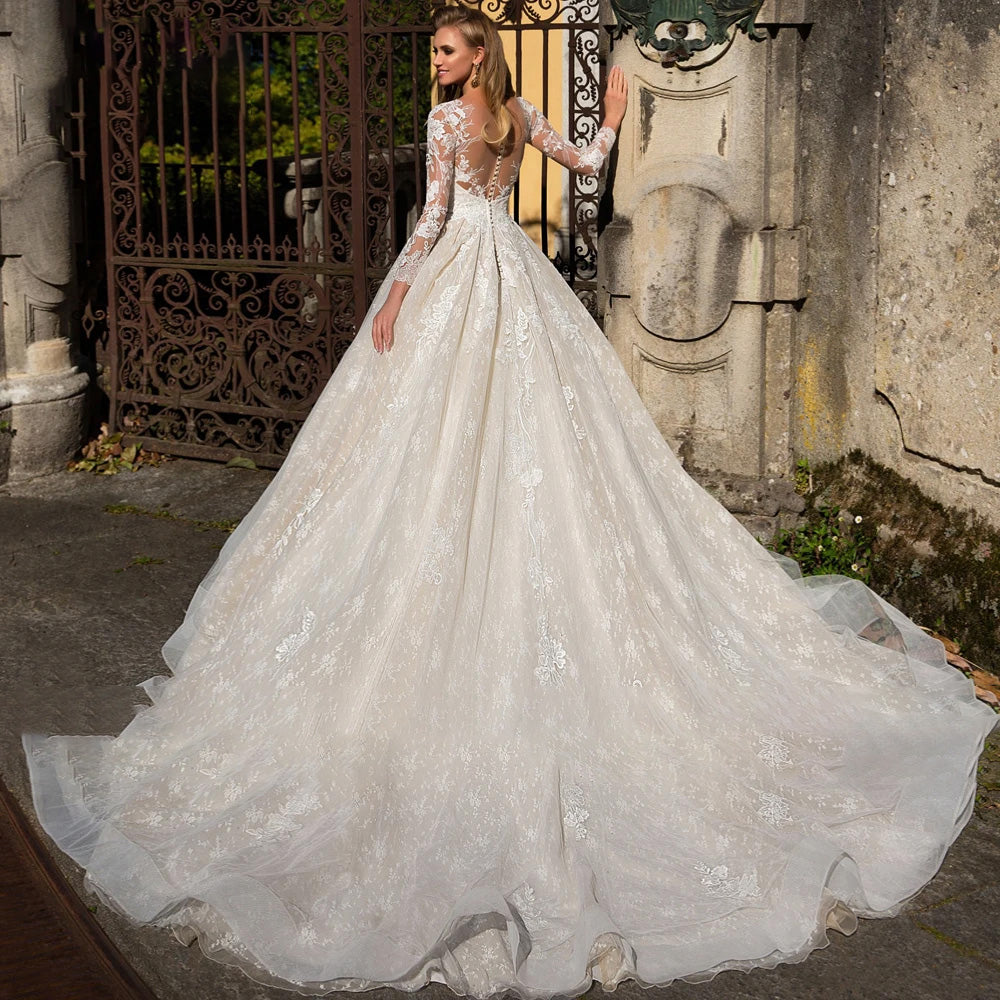 Back view of a stunning A-line court bridal gown showcasing a dramatic train and beautiful illusion lace back detailing.