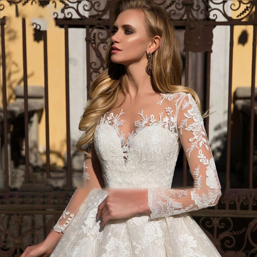 Close-up of the long sleeve illusion lace bodice on a luxury A-line bridal gown, highlighting the intricate floral appliques.