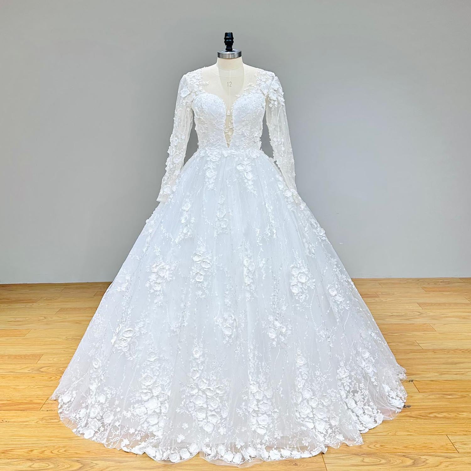 Front view of a long-sleeve floral lace ball gown wedding dress featuring delicate applique details and a sweetheart neckline on a mannequin.