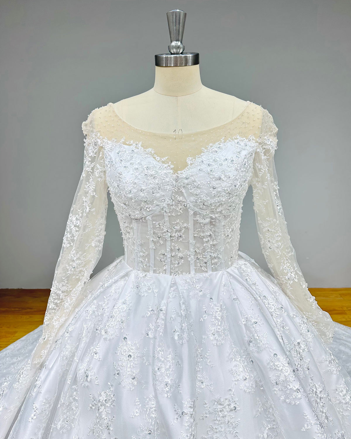 Close-up detail of a bridal bodice highlighting the intricate 3D floral lace embroidery on sheer mesh sleeves and a structured mesh corset waist.