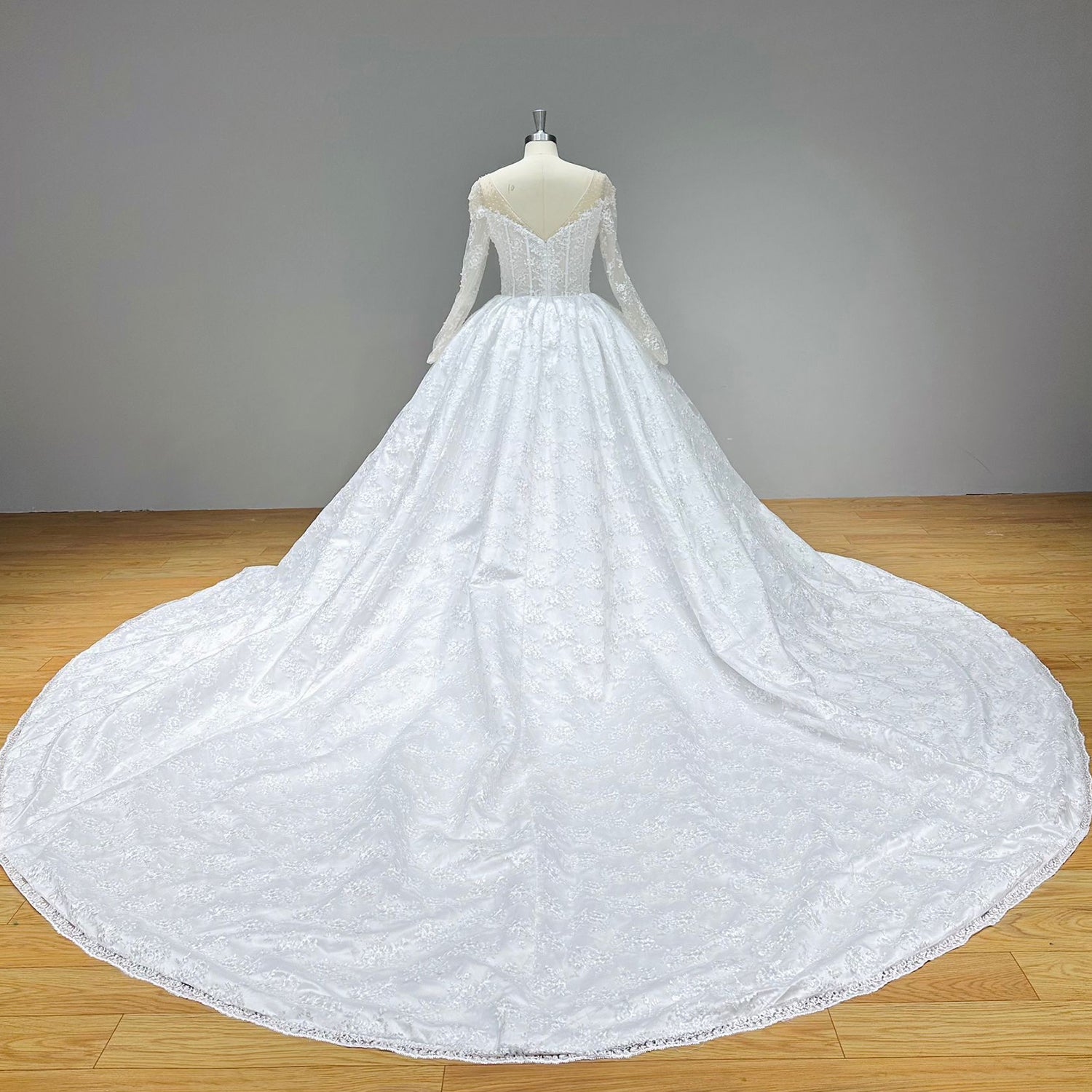 Detailed back perspective of an illusion lace bridal top on a dress form, emphasizing the seamless skin-toned mesh and traditional fabric-covered buttons.
