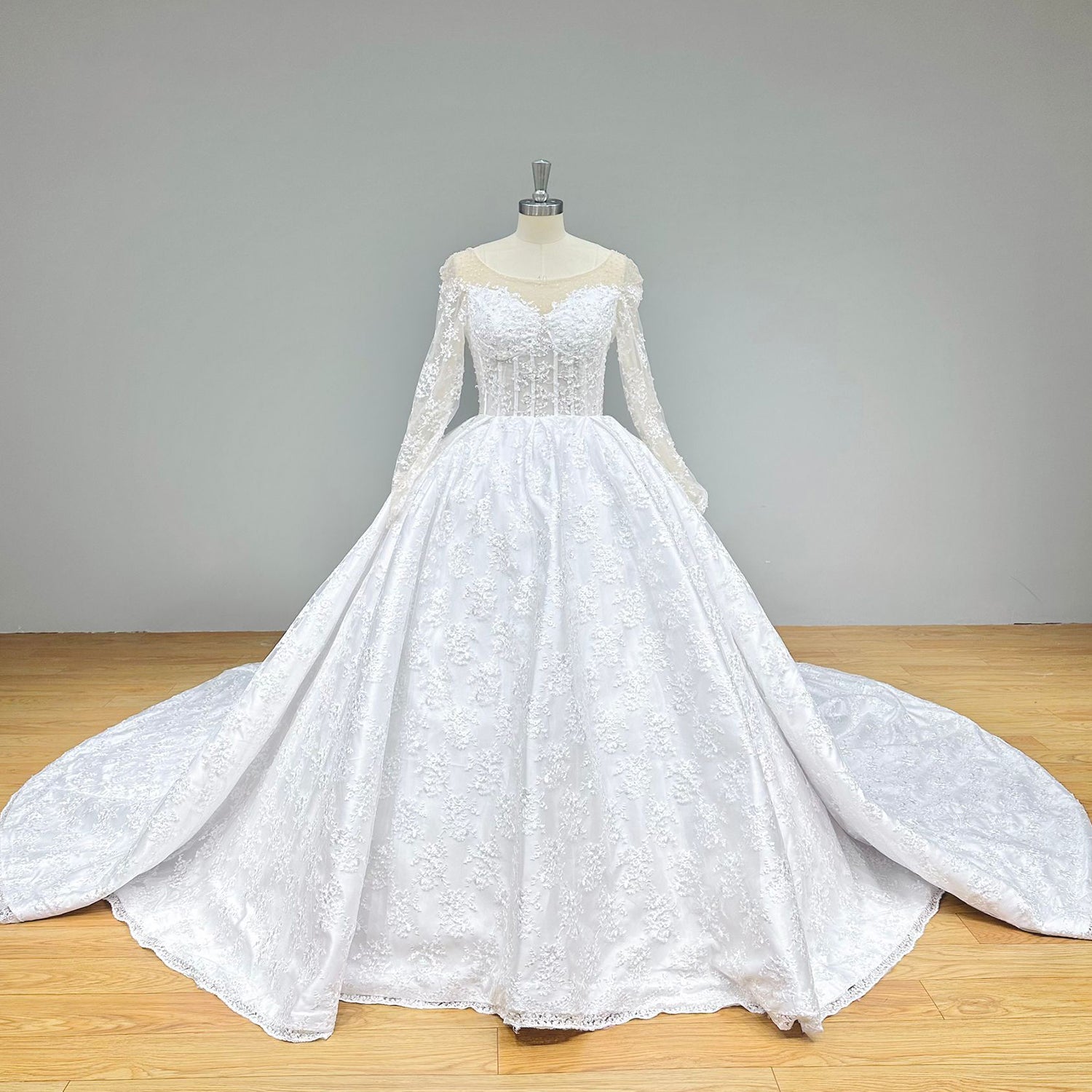 Full-length studio front portrait of the fairytale white lace and tulle princess bridal gown on a dress form against a neutral gray backdrop.