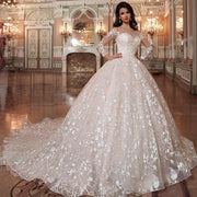 Elegant bride in a grand wedding venue wearing a long sleeve ball gown wedding dress, featuring a crystal beading belt and a modern cut-out back design.