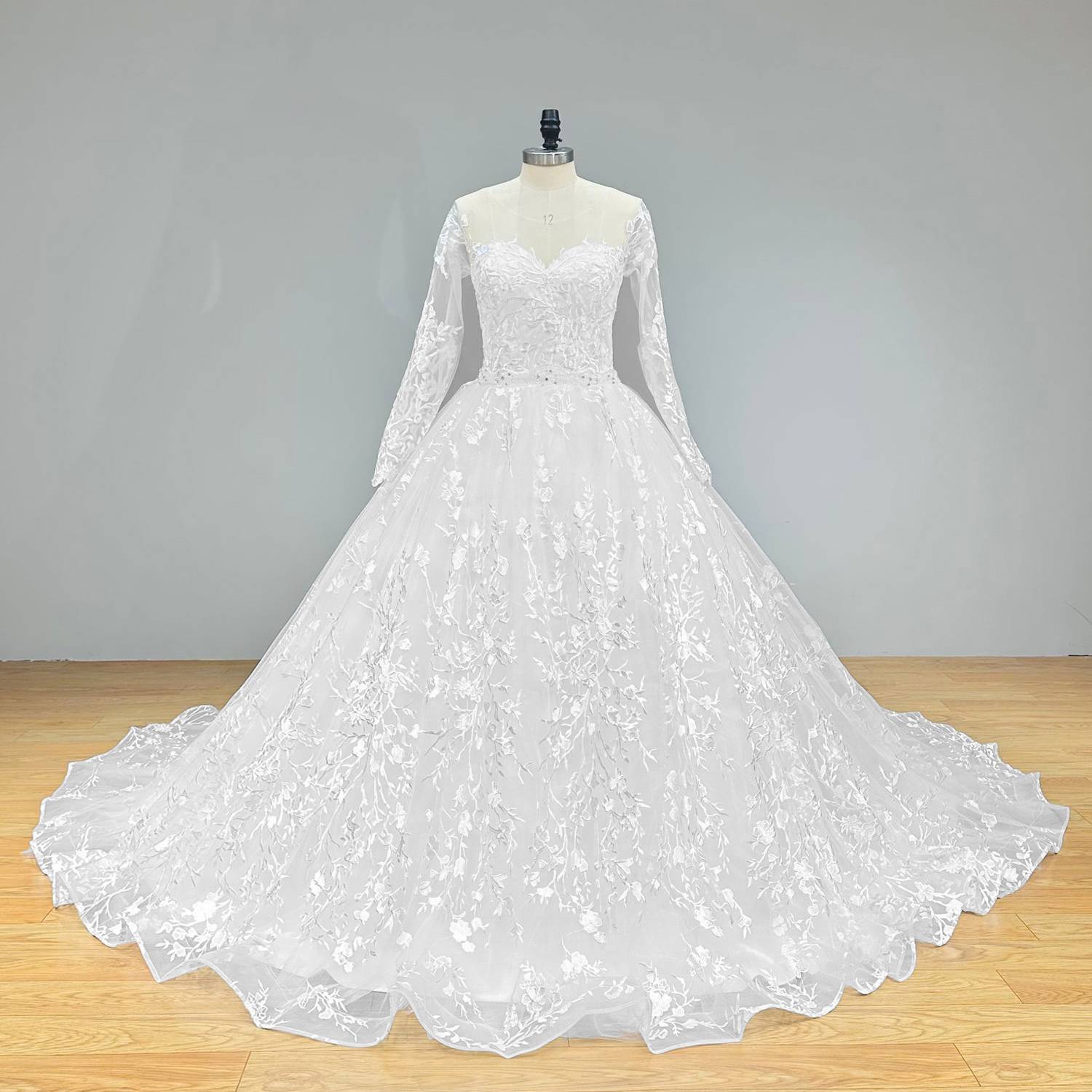 Sophisticated studio shot of a ball gown wedding dress on a mannequin, highlighting the clean lines of the long sleeves and the stunning focus point of the crystal beading belt at the waist.