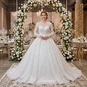 Smiling bride wearing a luxury long sleeve ball gown wedding dress with lace appliques, standing beneath a massive floral arch.