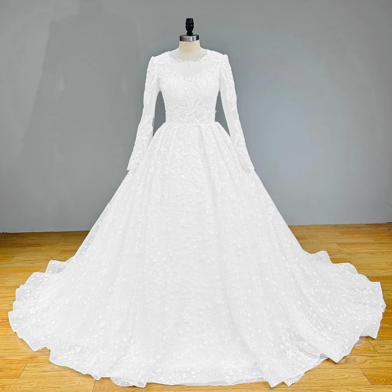 Front full-length view of a long sleeve bridal ball gown featuring detailed floral lace appliques on a showroom mannequin.