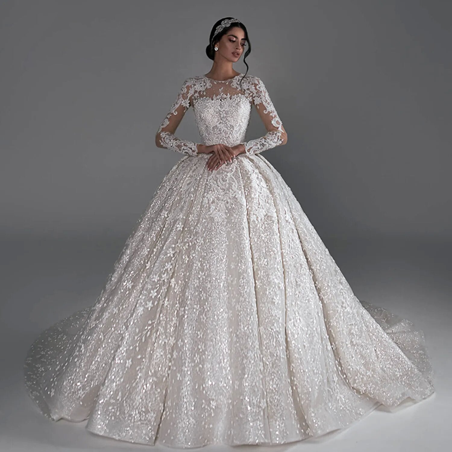 Studio bridal fashion portrait of a model in a magnificent long sleeve wedding dress with a classic princess silhouette.