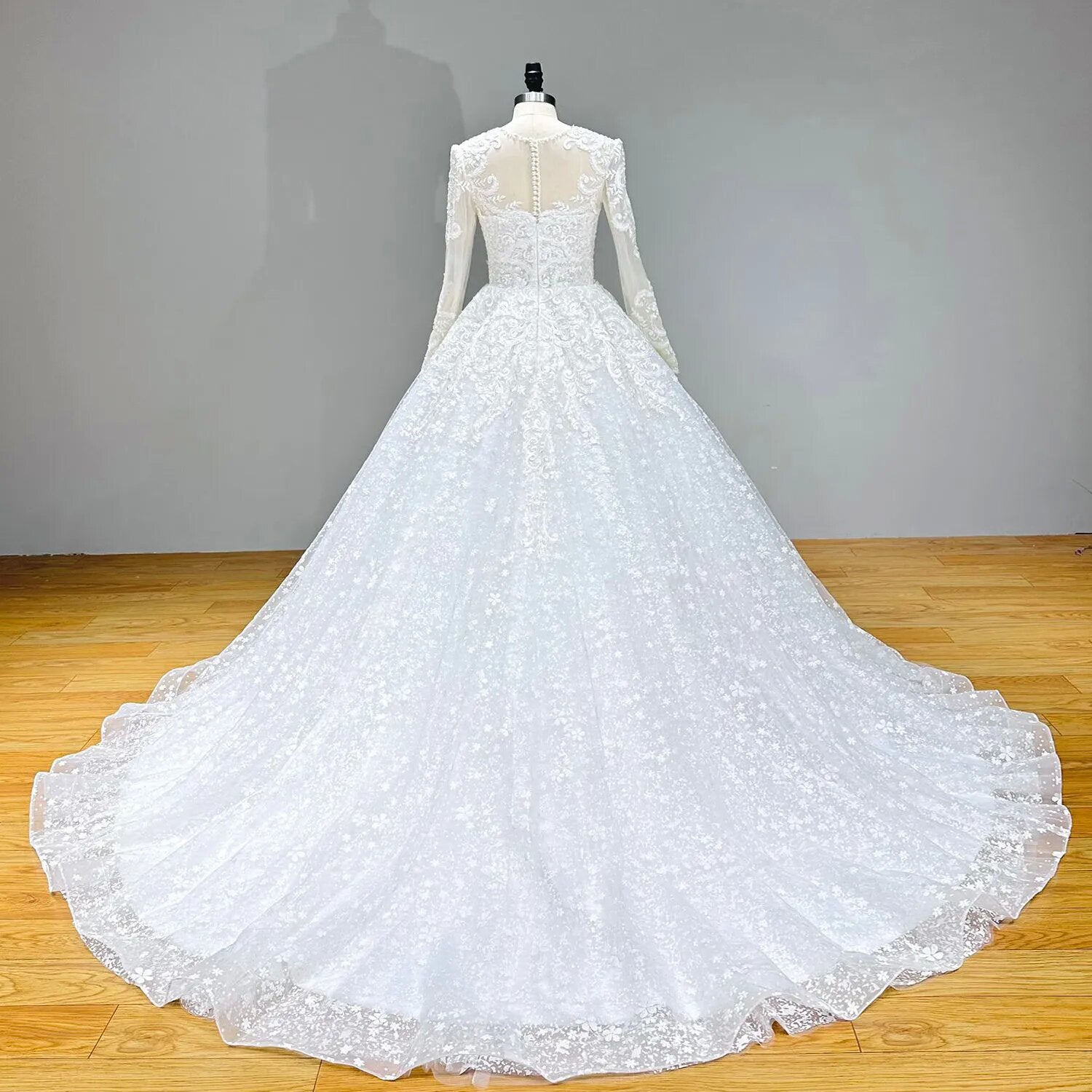 Full back product shot of a long sleeve ball gown wedding dress on a mannequin, highlighting an expansive lace train.