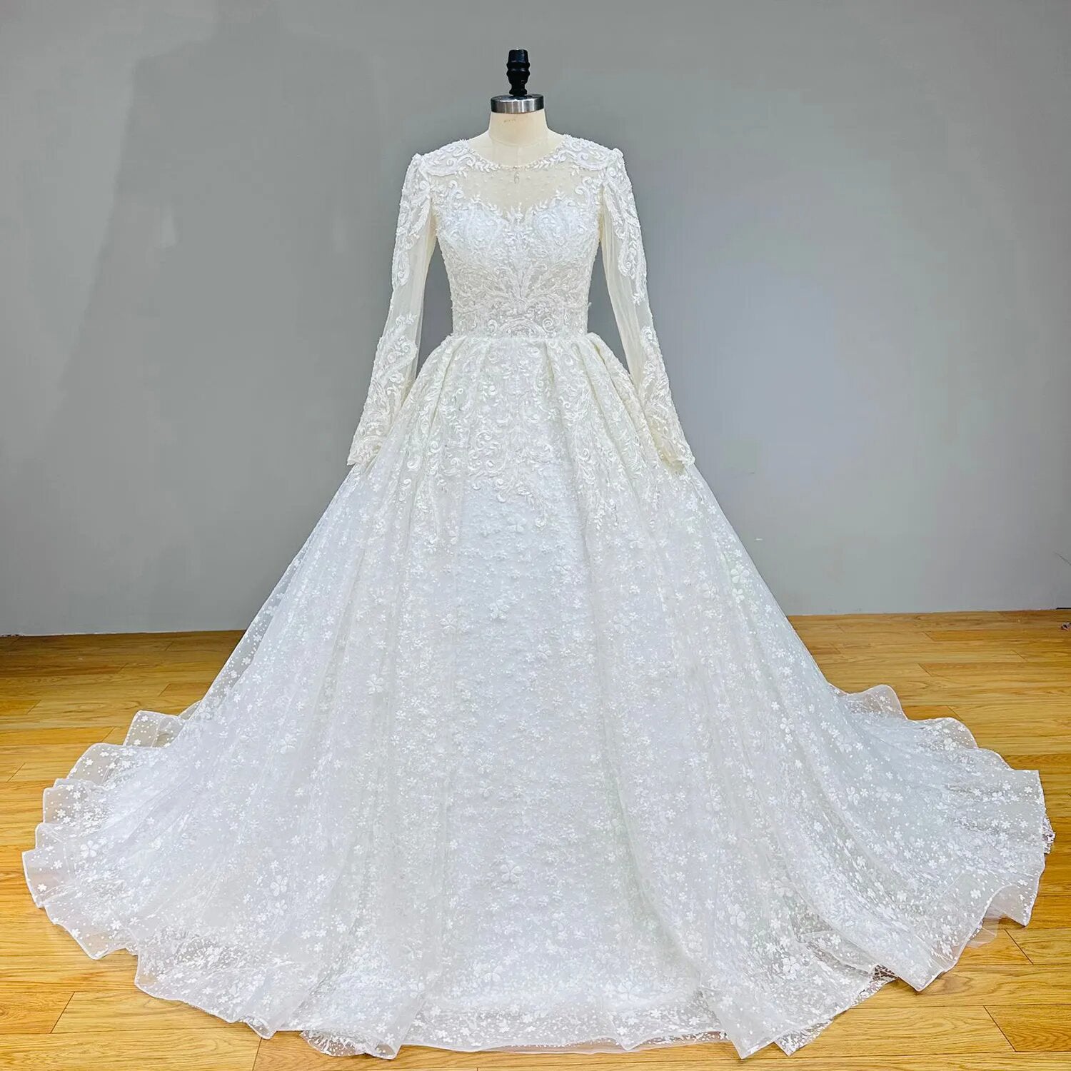 Standard front view of a white long sleeve ball gown wedding dress with all-over sparkle appliques on a studio mannequin.