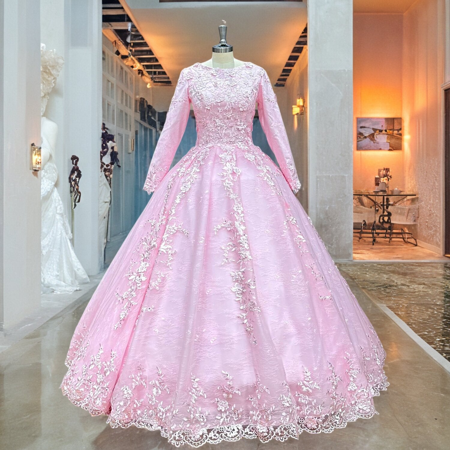 Luxury pink long-sleeve ball gown wedding dress featuring floral lace patterns and a voluminous tulle skirt displayed in a boutique showroom.