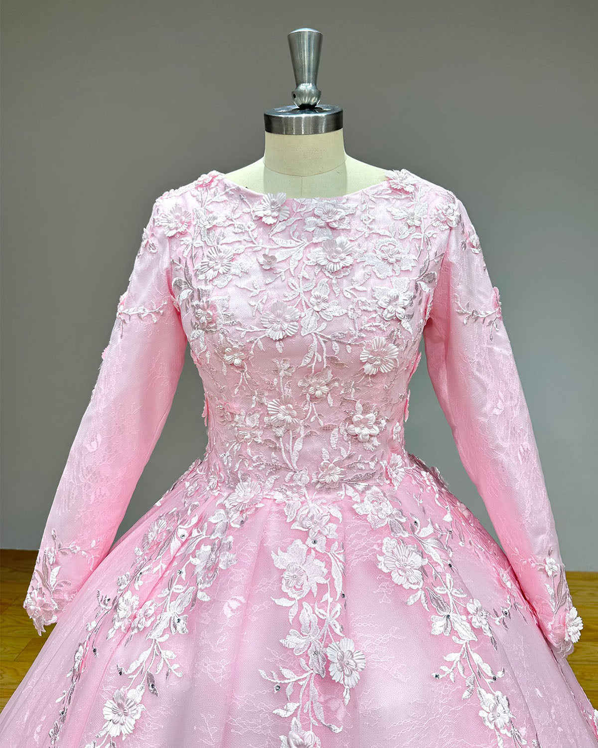 Detailed view of a pink high-neck bridal bodice embellished with dense 3D floral lace embroideries, beadwork, and subtle crystal clusters.