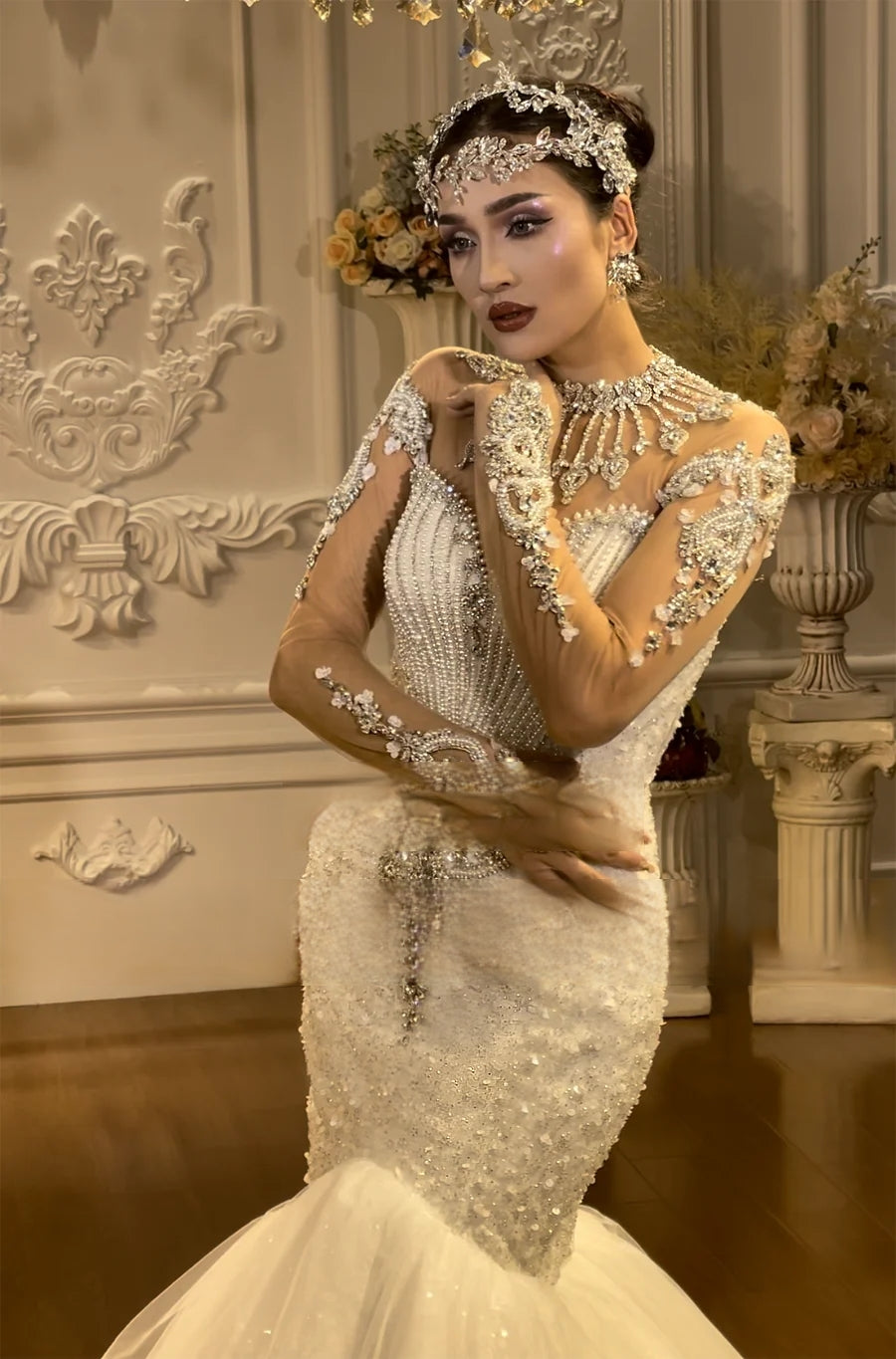 Close-up detail of a beaded mermaid wedding dress bodice showcasing premium pearls, crystals, sheer illusion sleeves with floral embroidery, and a sparkling jewel-encrusted collar.